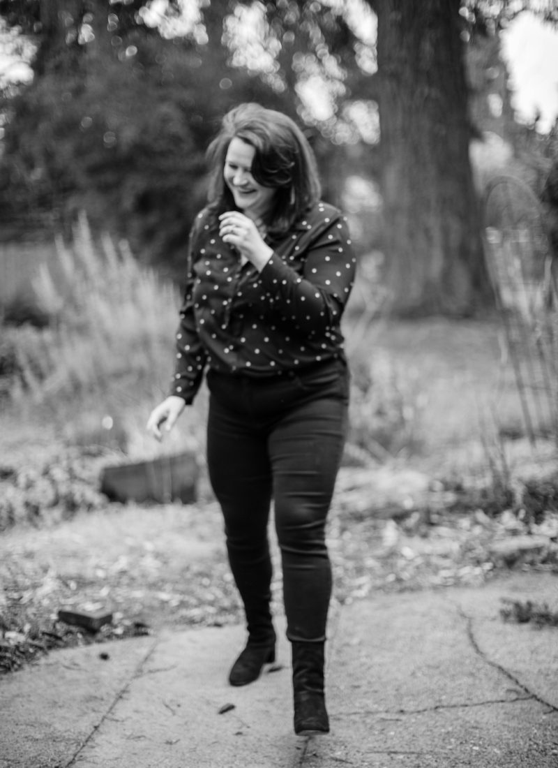 black and white image of a woman dressed in black pants and a black and white polka dot shirt smiling